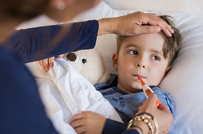 a sick boy having his temperature taken by his mother