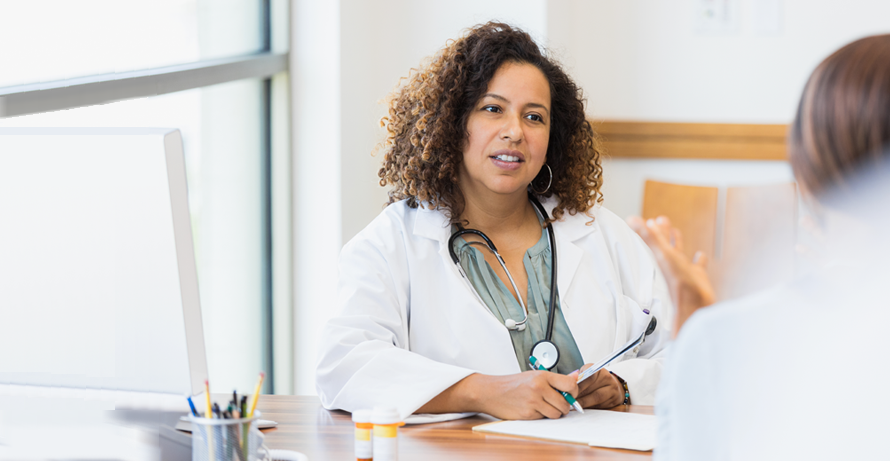 a doctor seated at her desk consulting with a patient