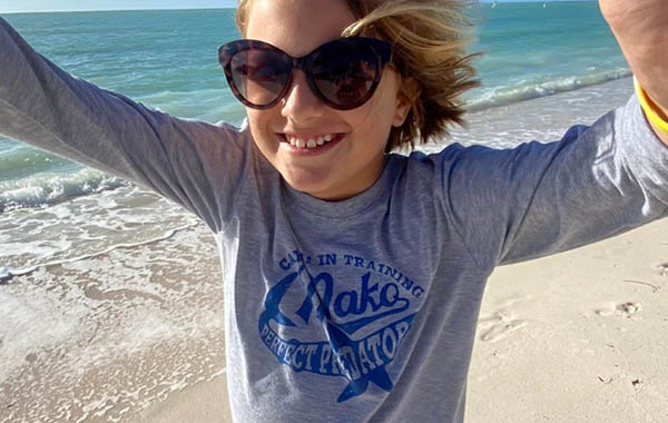 A young girl wearing sunglasses on the beach